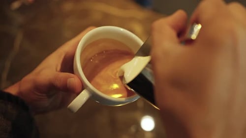 4K Close up of Barista hand pouring froth milk in espresso coffee making coffee latte in coffee cup.