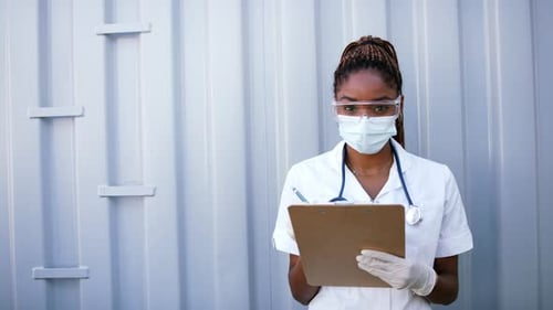 Medical Worker Writing on Clipboard Wearing PPE