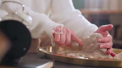 Explorer Sculpting Octopus Shape with Hands in Tray During Therapy Session