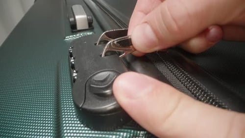 A Hand demonstrates how to use the combination lock, adjusting the code to unlock the zipper pulls