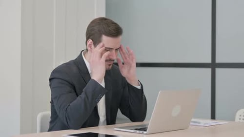 Man Working on Laptop Massages Temples