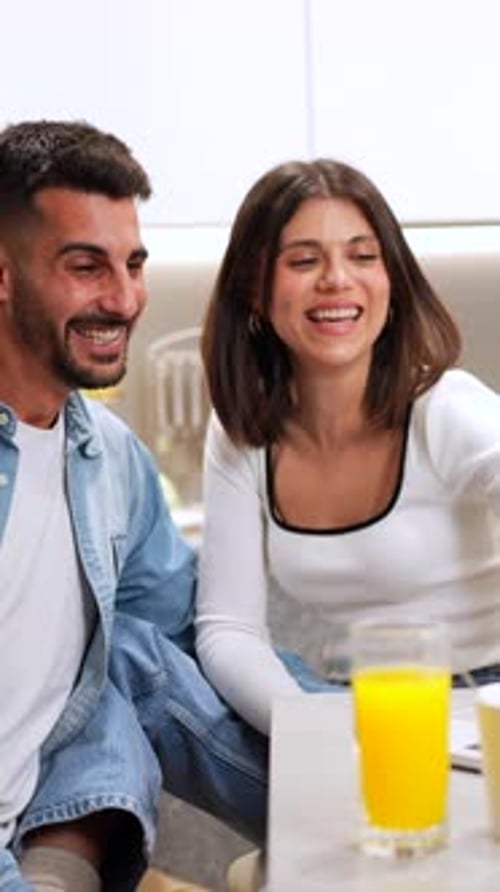 Happy Young Couple Using Laptop in Bright Kitchen