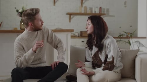 Young Couple Talking on Couch Indoors