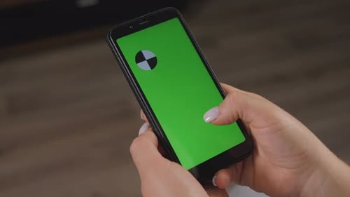 Closeup of Woman's Hand Browsing Smartphone with Green Screen at Home