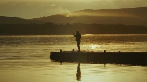 Lone Fisherman Casts Rod at Sunrise or Sunset