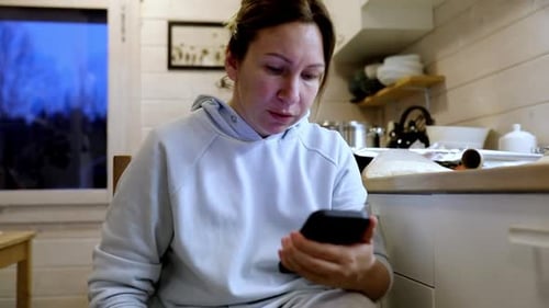 Woman Using Smartphone in a Rustic Kitchen