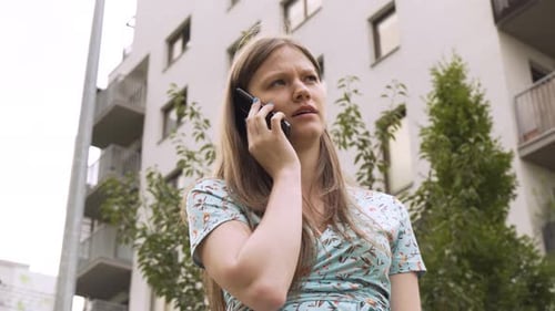 A Beautiful Young Caucasian Woman Talks on a Smartphone in a Suburban Area