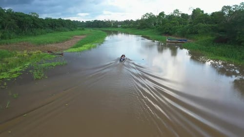 Foto de un Zumbido rastreando una pequeña embarcación que bajaba por el río Amazonas en la selva tropical con pájaros volando