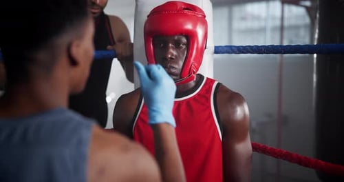 Boxer Receiving Adjustment from Coach in Boxing Ring
