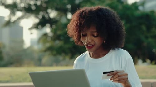 Portrait of African American Woman Inserting Credit Card Data Online in Park