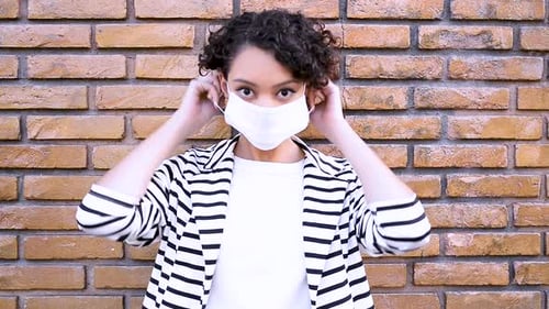 Brunette woman shows step by step how to put on mask to avoid contamination by SARS-CoV-2 coronaviru