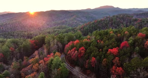 Car Cruising on Scenic Road in Appalachian Mountains at Sunset Trees Glowing in Vibrant Fall Foliage