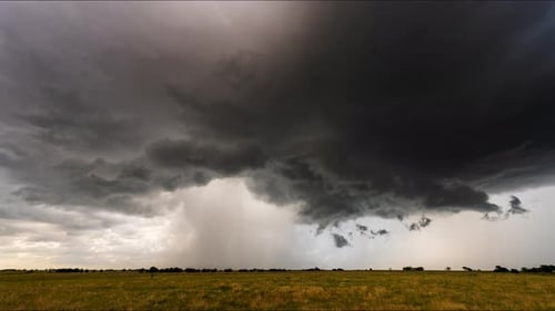Dramatic storm clouds over golden grassy field