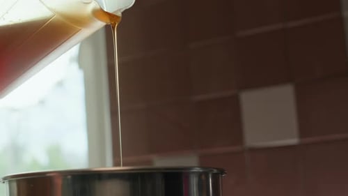 Pouring Golden Liquid into a Pot in Kitchen