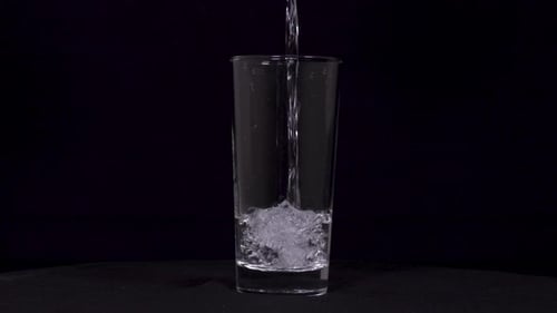 Water Pouring into Glass on Black Background