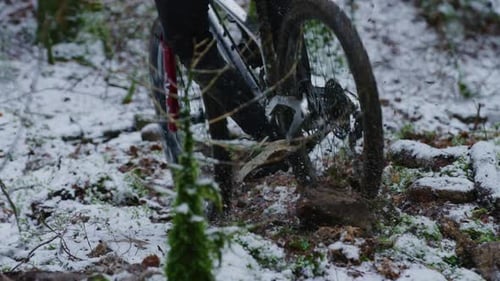 A mountain bike lifts a rock up with his rear wheel in the snow in slow motion