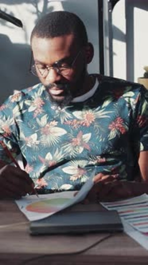 Man Reviews Documents at Bright Desk Indoors