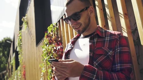 Man Leaning Against Building While Using Phone