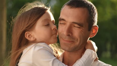 Girl Kisses Happy Father in Park Sunlight