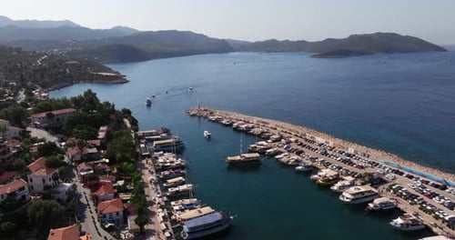 Aerial high angle view of Kas marina in Antalya, Turkey, with boats, blue waters, and lush hills sur