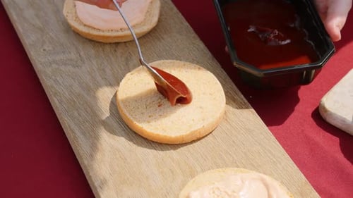Red Sauce Being Added to Hamburger Bun