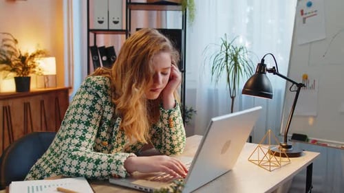 Bored Sleepy Businesswoman Worker Working on Laptop Computer Yawns Leaning on Hand at Office Desk