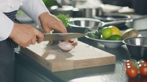Close-up of a Chef Masterfully Cutting Colorful Vegetables and Onions on Cutting Board.
