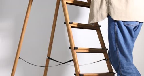 Adult Climbs Wooden Ladder in Bright Studio