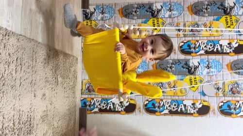 Happy Infant Playing in a Yellow Swing Indoors