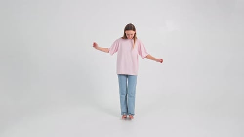 Woman in Jeans and Tshirt is Going on Heels Trying Not to Fall and Holding Hands in Sides