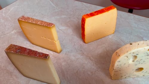 Various types of cheese are on a kitchen table.