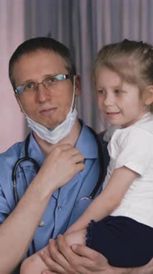 Doctor Holding Child in Hospital Room