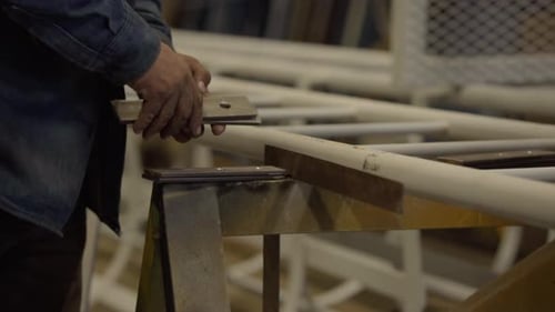 Schweißerhand, die ein Metallstück in der Werkstatt hält. - Nahaufnahme
