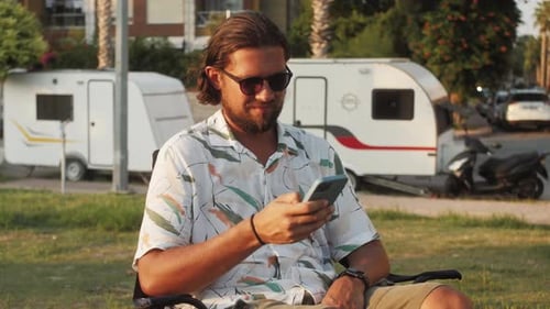 Man Using Mobile Phone Outdoors Near Travel Trailers