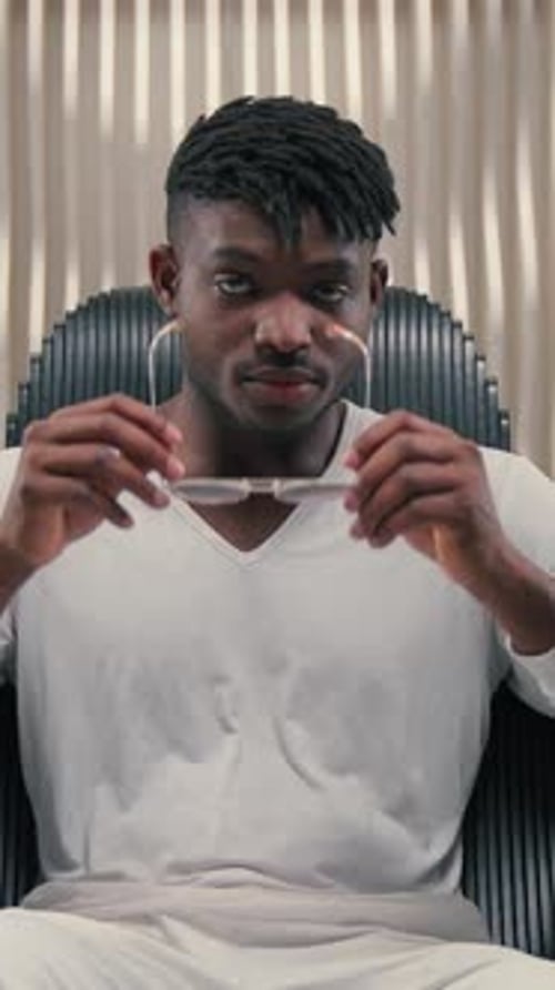 Young Man Puts on Sunglasses and Looks at Camera