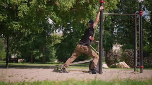 Man Stretches at Outdoor Exercise Equipment on Sunny Day