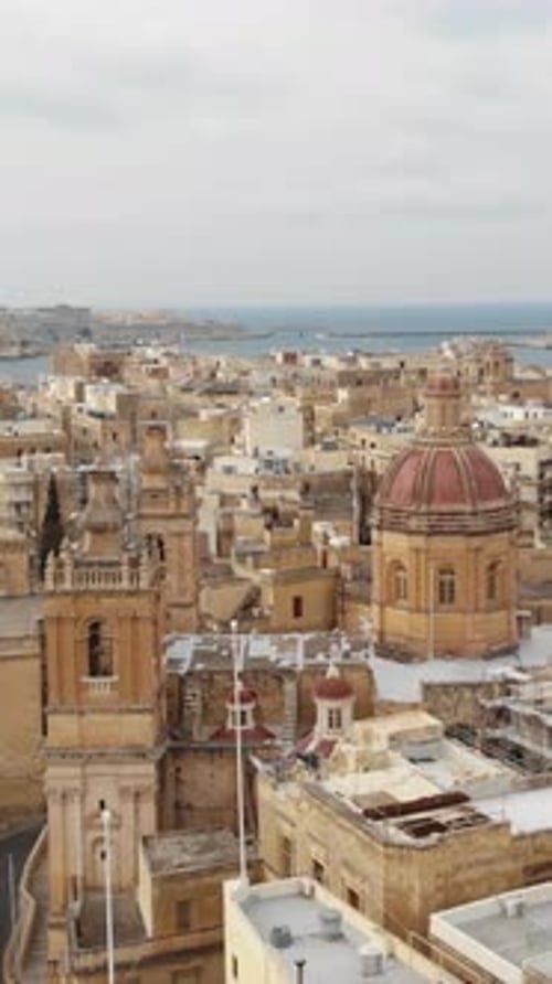 Aerial view of St Lawrence Collegiate Church dominating Vittoriosa cityscape in Malta. Vertical shot