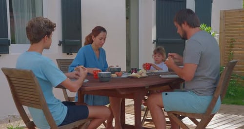 Family Eating Breakfast Together at Outdoor Table