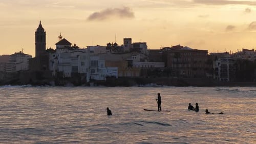 Silhouette a Group of Surfers Paddling Over a Ocean Wave Surf Session During Sunset