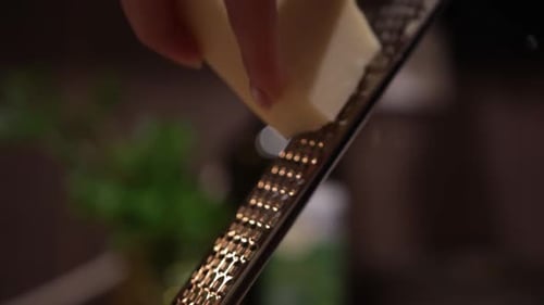 Grating Block Of Cheese With Cheese Grater. closeup, slow motion