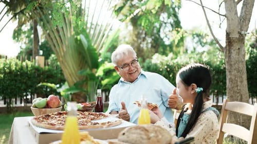 Family Eating Pizza Outdoors on Sunny Day