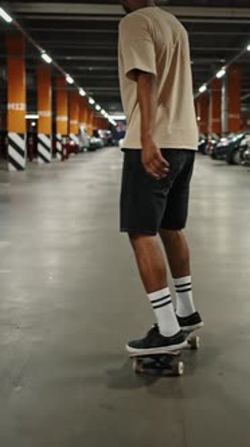 Follow Shot of Young Cool African American Guy Riding Skateboard at Underground Parking Area Back