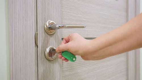 Young Woman Unlocks Wooden Door with Key and Enters Indoors