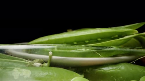Poured cleaned peas into a plate on a black background. Dolly slider, close-up.
