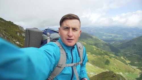 Man Takes a Selfie with a Camera During a Vacation in the Mountains While Hiking