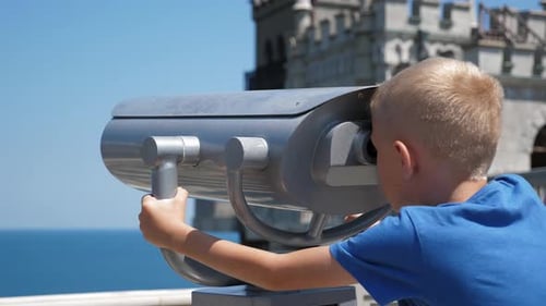Boy Looking Through Binoculars Near the Sea