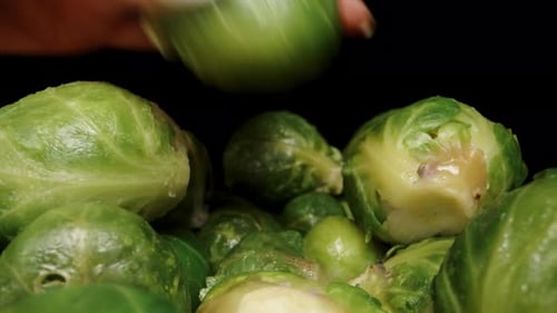 Mountains of cooked Brussels sprouts, as the camera moves forward and a woman's hand picks them up