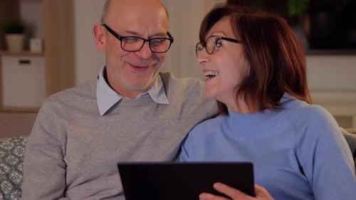 Senior Couple Smiling Using a Tablet Device at Home