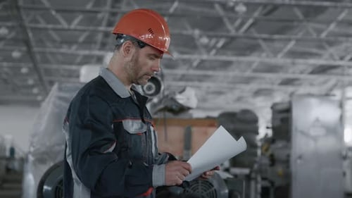 Factory Worker Reviews Plans Wearing Hard Hat