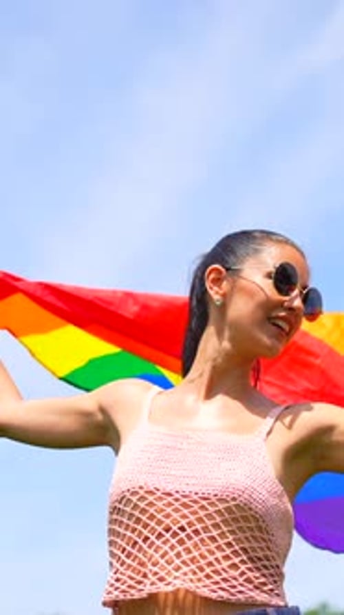 Woman Waves Rainbow Flag on Sunny Day